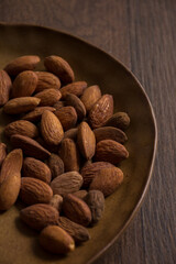Nuts on plate on dark brown wooden table