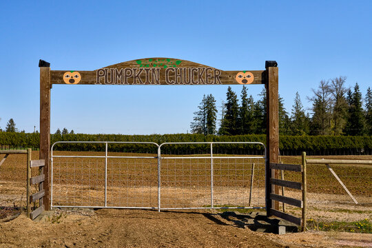 A large wooden arch that states pumpkin chucker in an empty field that will become a pumpkin patch.