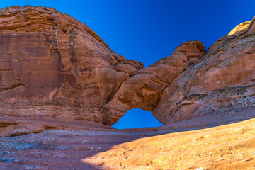 Tall rock formation with an arch carved into it against the sky at Arches National Park, Utah