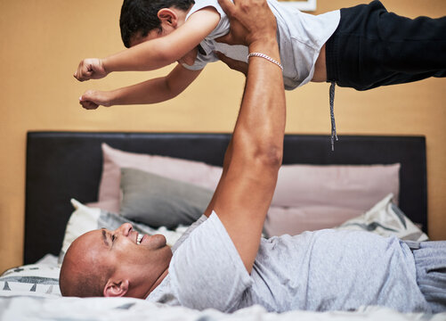 Happy father, lifting son and playing with excited for entertainment in home as family in bonding. Man, boy and fun for activity in together for superhero, childhood development and growth in bedroom