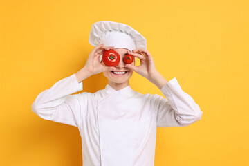 Professional chef with fresh tomatoes having fun on yellow background