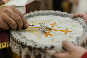 Priest holding the cross near wedding rings during a traditional Armenian wedding ceremony