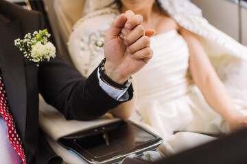 Newlyweds seated in a car, holding hands