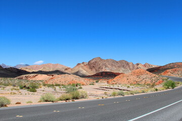 Road with a mountain backdrop under clear blue skies. Valley of Fire State Park, Nevada, USA