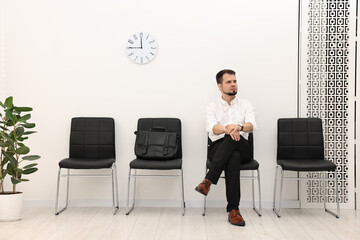 Fototapeta premium Man sitting on chair and waiting for job interview indoors