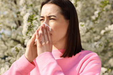 Woman with napkin suffering from seasonal allergy on spring day