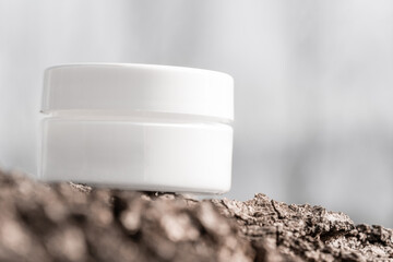 white cosmetic jar on tree bark