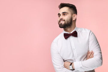 Portrait of smiling man in shirt and bow tie on pink background. Space for text