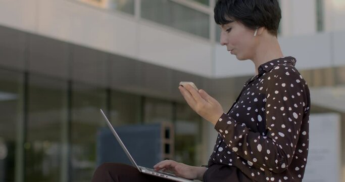 Woman using smartphone against urban backdrop. Technology and modern lifestyle. Sense of connectivity, efficiency, and adaptability humans in the digital era. AI chat bot assistent using.