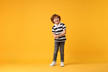 Happy little boy dancing on yellow background