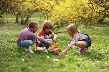 Fototapeta premium Easter celebration. Cute little children hunting eggs outdoors