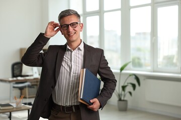 Happy man with notebooks in office, space for text
