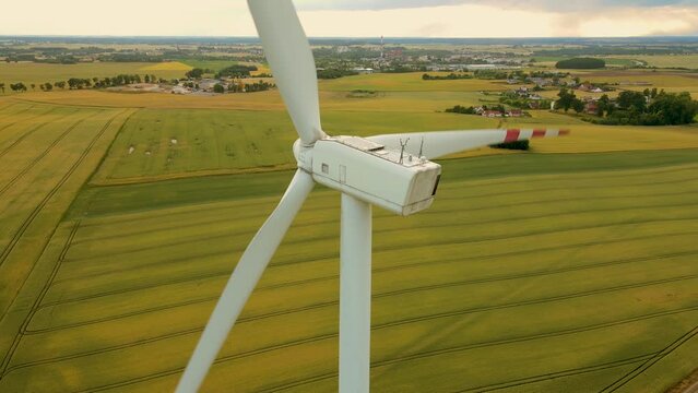 Aerial View Wind Turbine in Ripening green wheat Field. Rotating blades generate clean electric power. Popularization of renewable energy sources and sustainable development