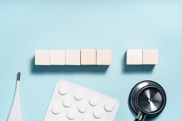 Medical items and wooden blocks on light blue background