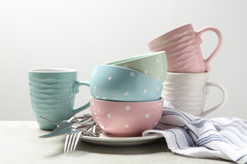 Beautiful ceramic dishware, cups and cutlery on light grey table