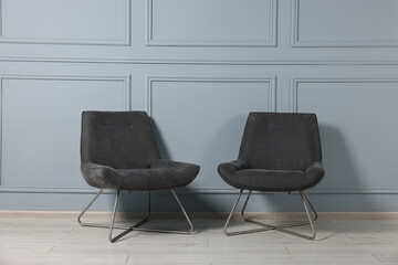 Fototapeta premium Comfortable armchairs near grey wall in room