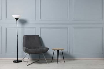 Comfortable armchair, side table and lamp indoors, space for text