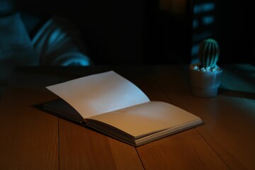 Open book on wooden table at night