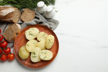 Plate with young boiled potatoes, dill and products on white table, flat lay. Space for text
