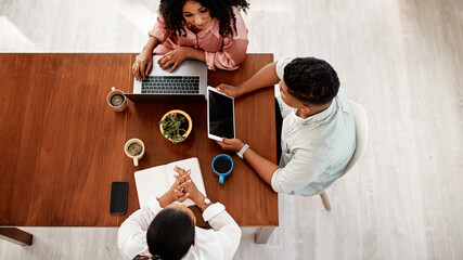 Digital technology, creative team and meeting at table for brainstorming, planning and collaboration from above. Laptop, tablet and notebook in office with group, scheduling and support in company