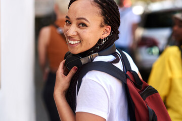 African woman, student and portrait in street with smile, backpack and headphones for music...