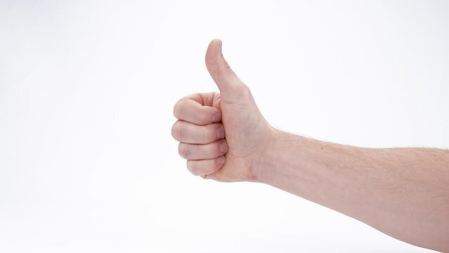 Young caucasian male hand gives a thumbs up hand gesture against a white background.