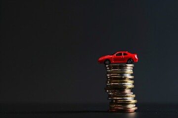 a red toy car on top of a stack of coins