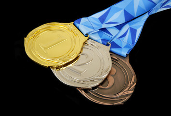 Gold, silver and bronze medals with ribbons isolated on black