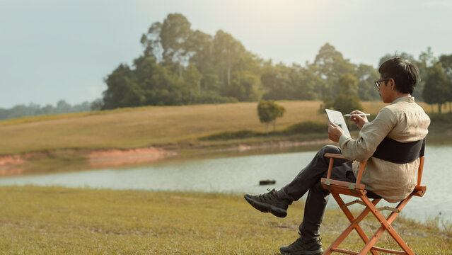 Content creator on director chair and writing script or production design with digital tablet to create new project in beautiful location.