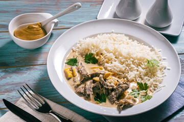 Beef Stroganoff with rice on plate with mustard