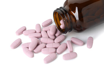 Scattered vitamin pills and bottle isolated on white