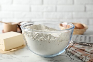 Making shortcrust pastry. Flour in bowl, butter and whisk on white marble table