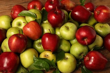 Fresh ripe apples with leaves on wooden table