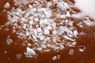 Delicious caramel sauce with sea salt as background, closeup