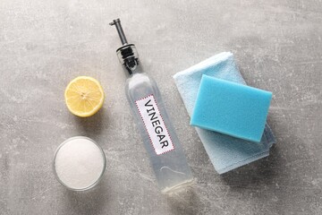 Natural cleaning products. Vinegar in bottle, baking soda, lemon, rag and sponge on grey textured...
