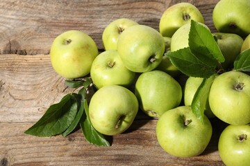 Many fresh apples and leaves on wooden table, above view