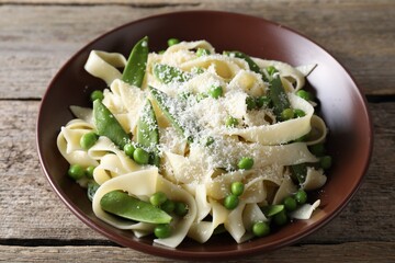 Delicious pasta with green peas and cheese on wooden table