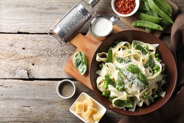 Delicious pasta with green peas and ingredients on wooden table, flat lay. Space for text