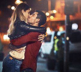 Couple, hug and kiss in city at night for bonding, romance on date as partners in love or...
