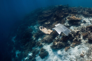 Freediver girl in tropical blue sea. Sexy woman freediver in bikini swims underwater in Maldives