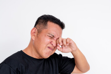 Obraz premium Image of a middle aged Asian man expressing discomfort while rubbing his irritated eyes, isolated on a white background.