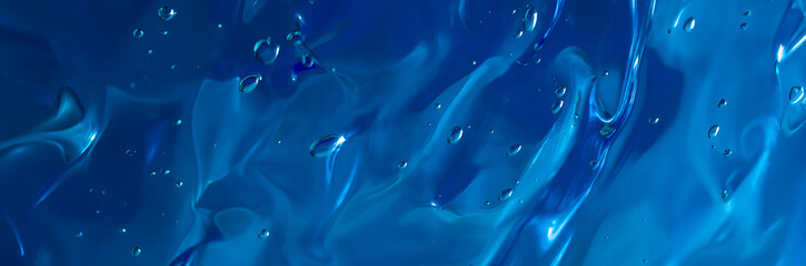Close up gel texture of cosmetic products. transparent cream on a dark blue background with...