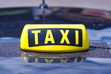 Close-up of yellow and black taxi sign on car roof of cab parked at taxi stand at Swiss City of...