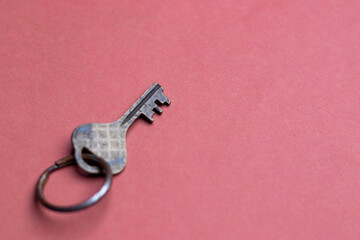 A metal key on a pink background with space fro text