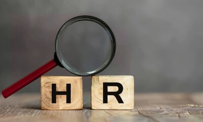 A magnifying glass over two wooden blocks with the word HR