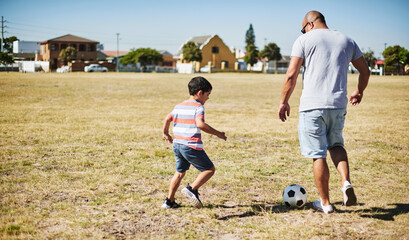 Father, son and playing with soccer ball for sports, fitness in park as family in bonding. Man, boy...
