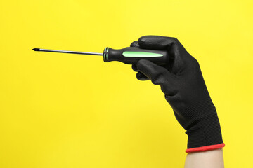 Woman holding screwdriver on yellow background, closeup