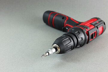 Modern cordless electric screwdriver on grey background, closeup. Space for text
