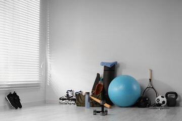 Many different sports equipment near wall indoors
