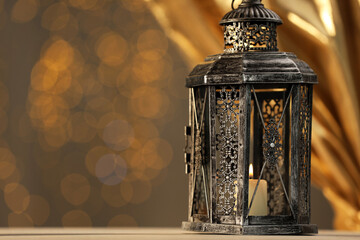 Arabic lantern on table against blurred lights, space for text